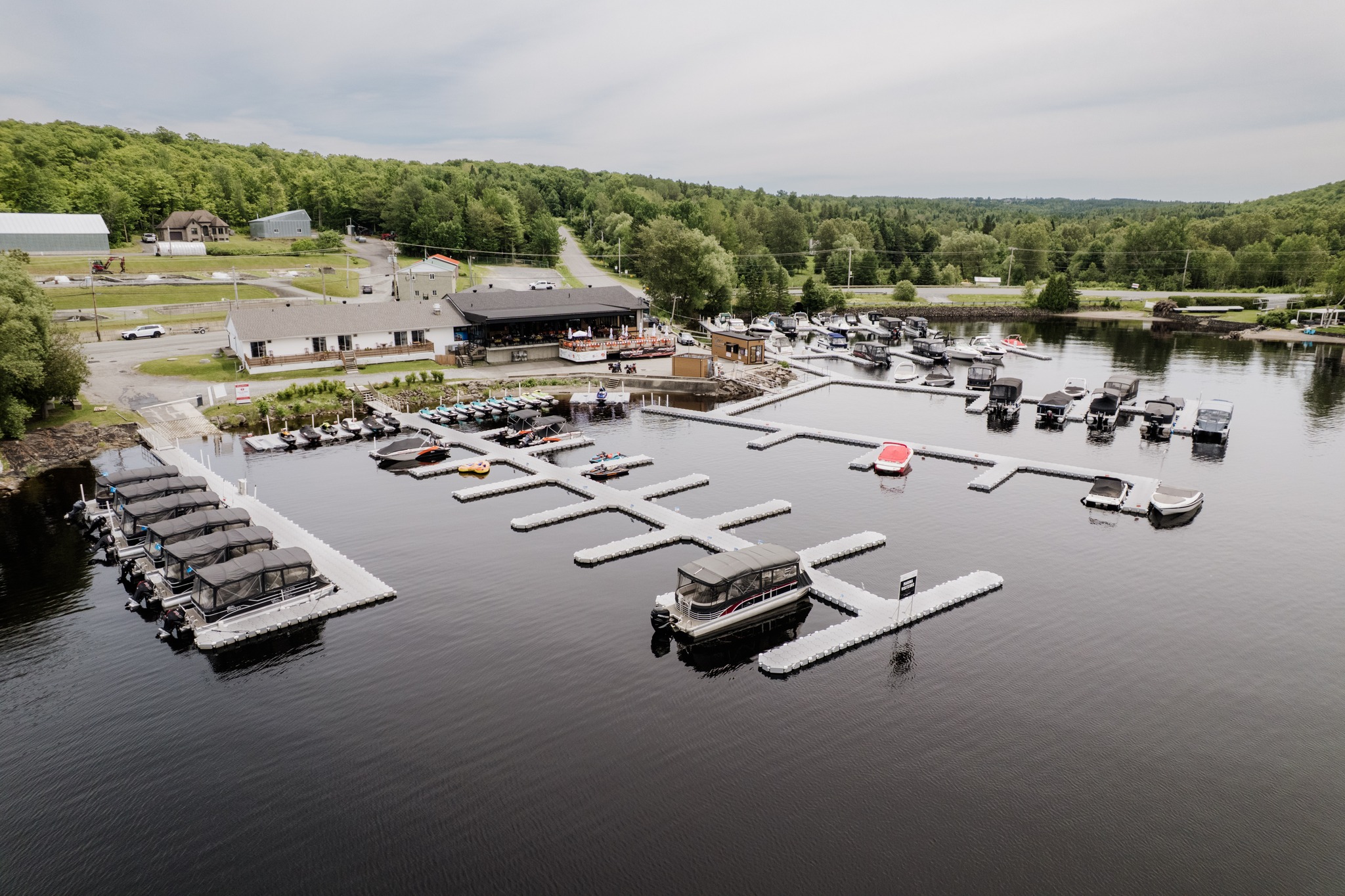 Aerial view of a waterfront marina with floating docks, boats, and wooded shoreline